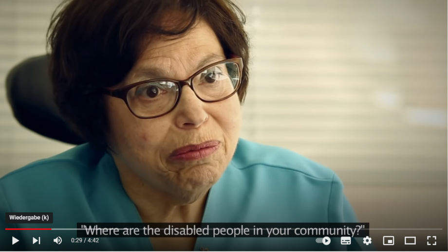 A close-up of an older women who is talking in the camera. This video will open in YouTube.