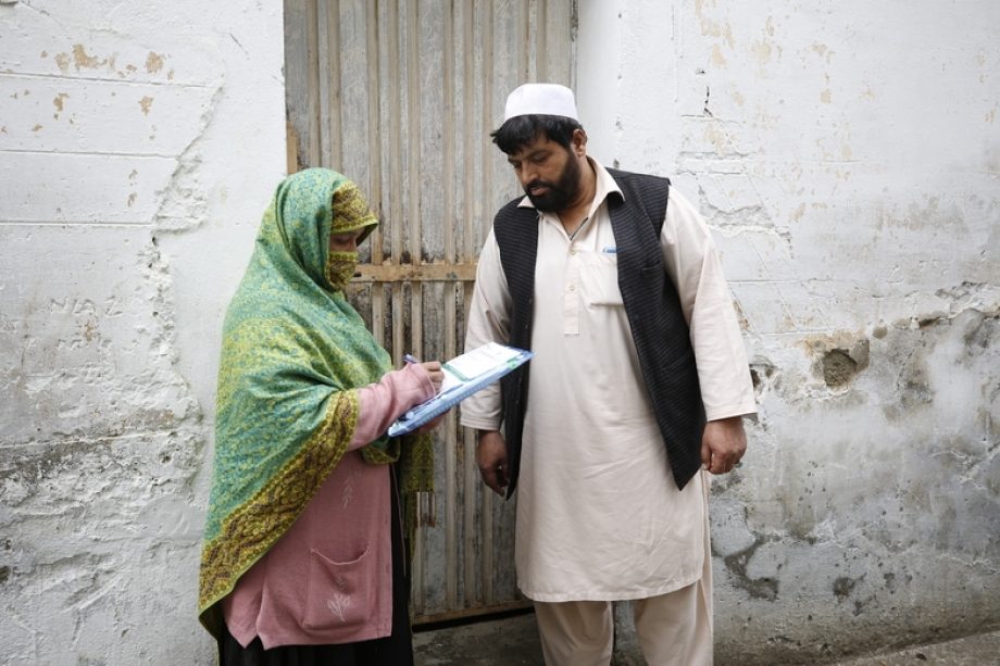 A woman asking survey questions to a man in front of his house